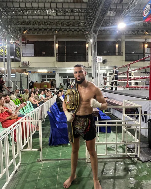 Amine, mains bandées, la ceinture Fairtex Fight sur l'épaule au bord du ring